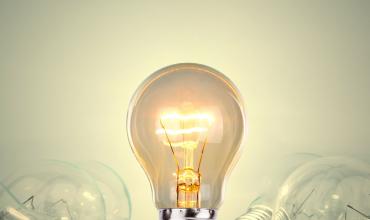 Staande, brandende gloeilamp tussen liggende gloeilampen zonder licht